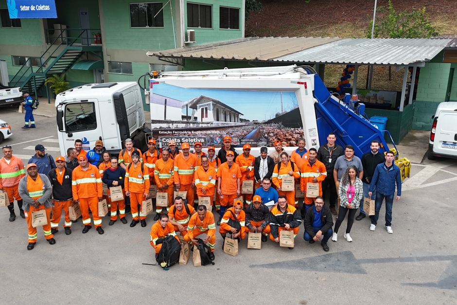 Agentes ambientais da Urbam (uniformizados de laranja) se reunem em frente ao caminhão da coleta para tirar uma foto