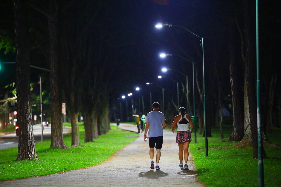 Casal calminha com segurança em calçada iluminada a noite em São José dos Campos