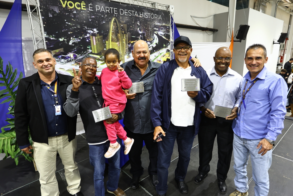 Funcionários homenageados exibem placas de reconhecimento ao trabalho